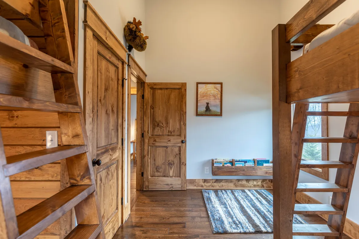 A cozy nook with built-in bunk beds, wooden stairs, a bookshelf, and cheerful wall art. The details—like the lending library—underscore the space's suitability for quiet reading, playtime, and winding down after mountain adventures.