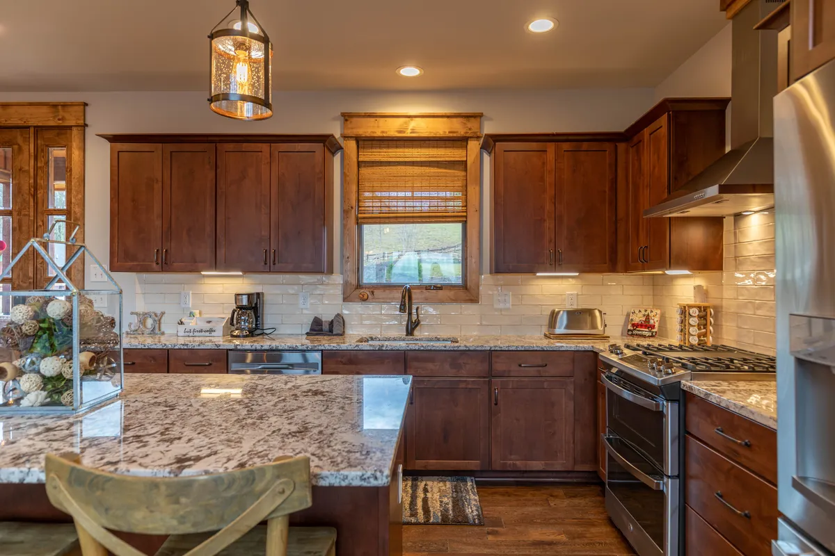 A modern kitchen with granite countertops, wooden cabinetry, and stainless steel appliances. The layout is inviting for group cooking, entertaining, and sharing gourmet meals after a day of exploration.